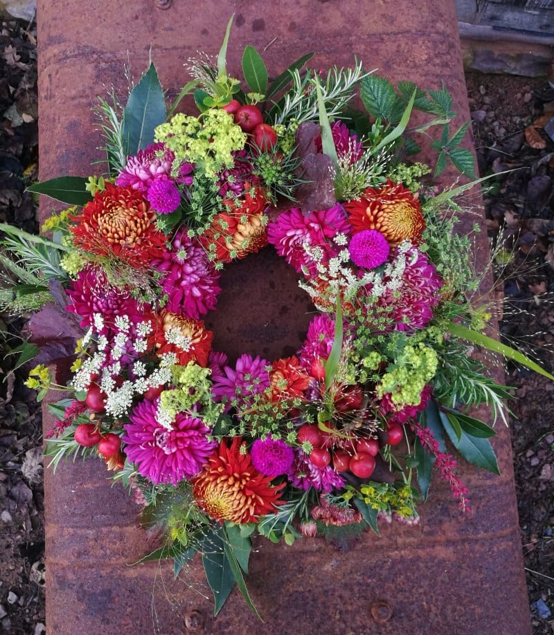 A bright autumn funeral wreath with chrysanthemums and dahlias by Farhill Flowers.