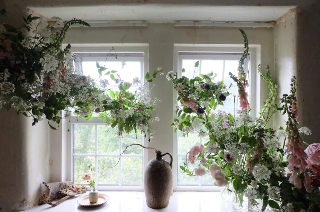 An ethereal window display of soft apricot foxgloves, scented roses and soft white lacy orlaya. Firenza Flowers.