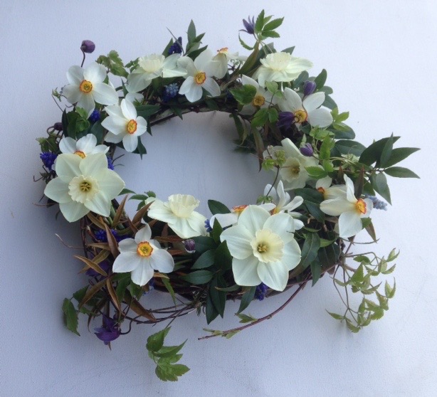 A delicate woven funeral wreath decorated with simple spring narcissi by Mayfield Flowers