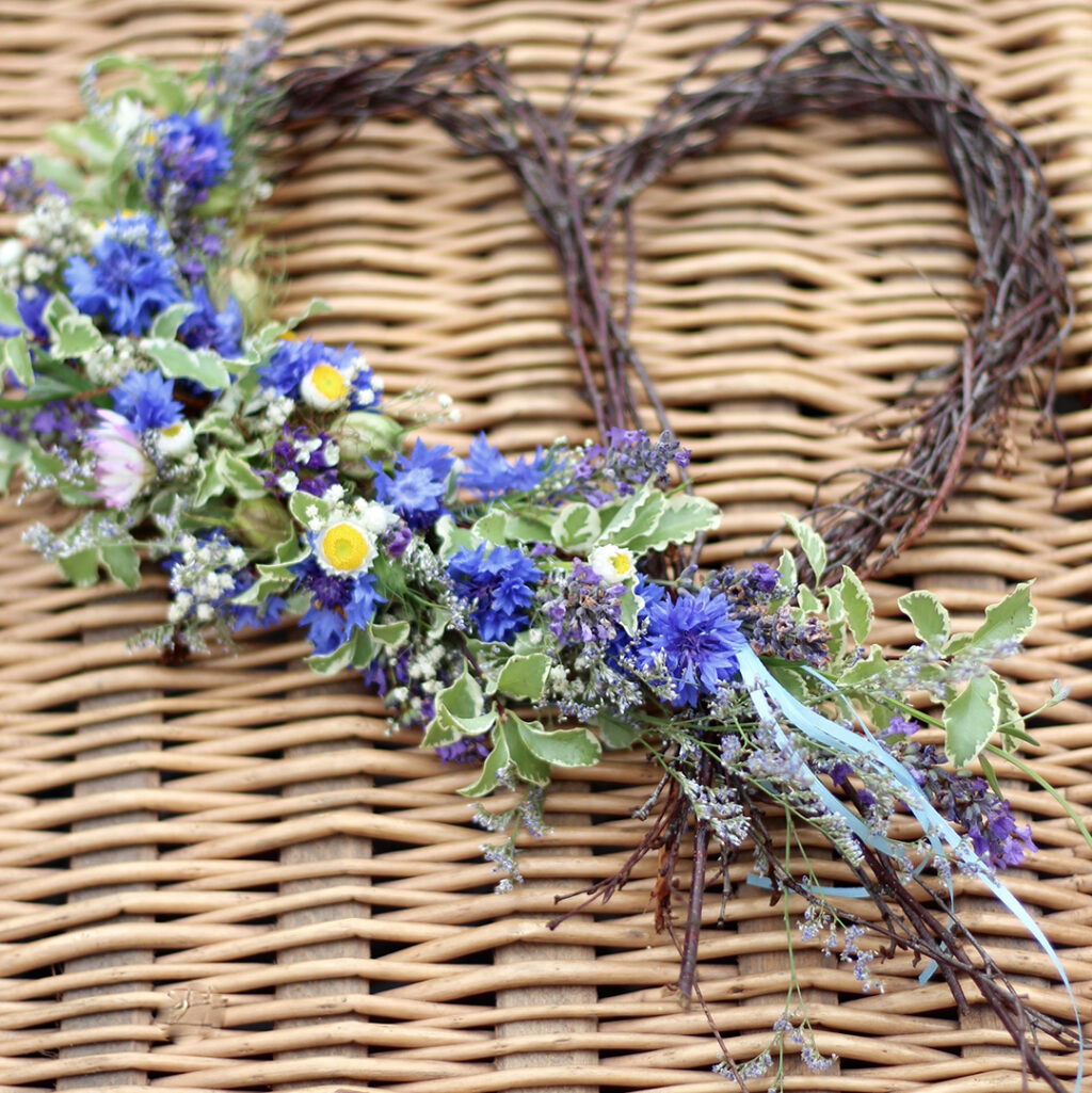 A heart wreath for a funeral decorated with cornflowers by Tuckshop Flowers