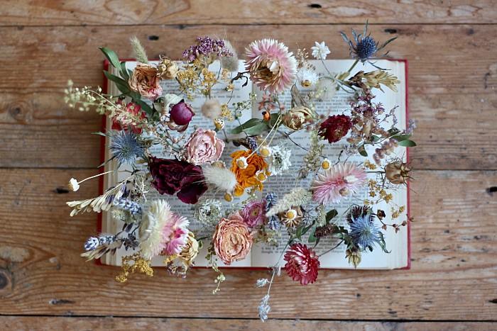 A book table centrepiece holds dried flower as if they are growing in a garden. Tuckshop Flowers, Birmingham