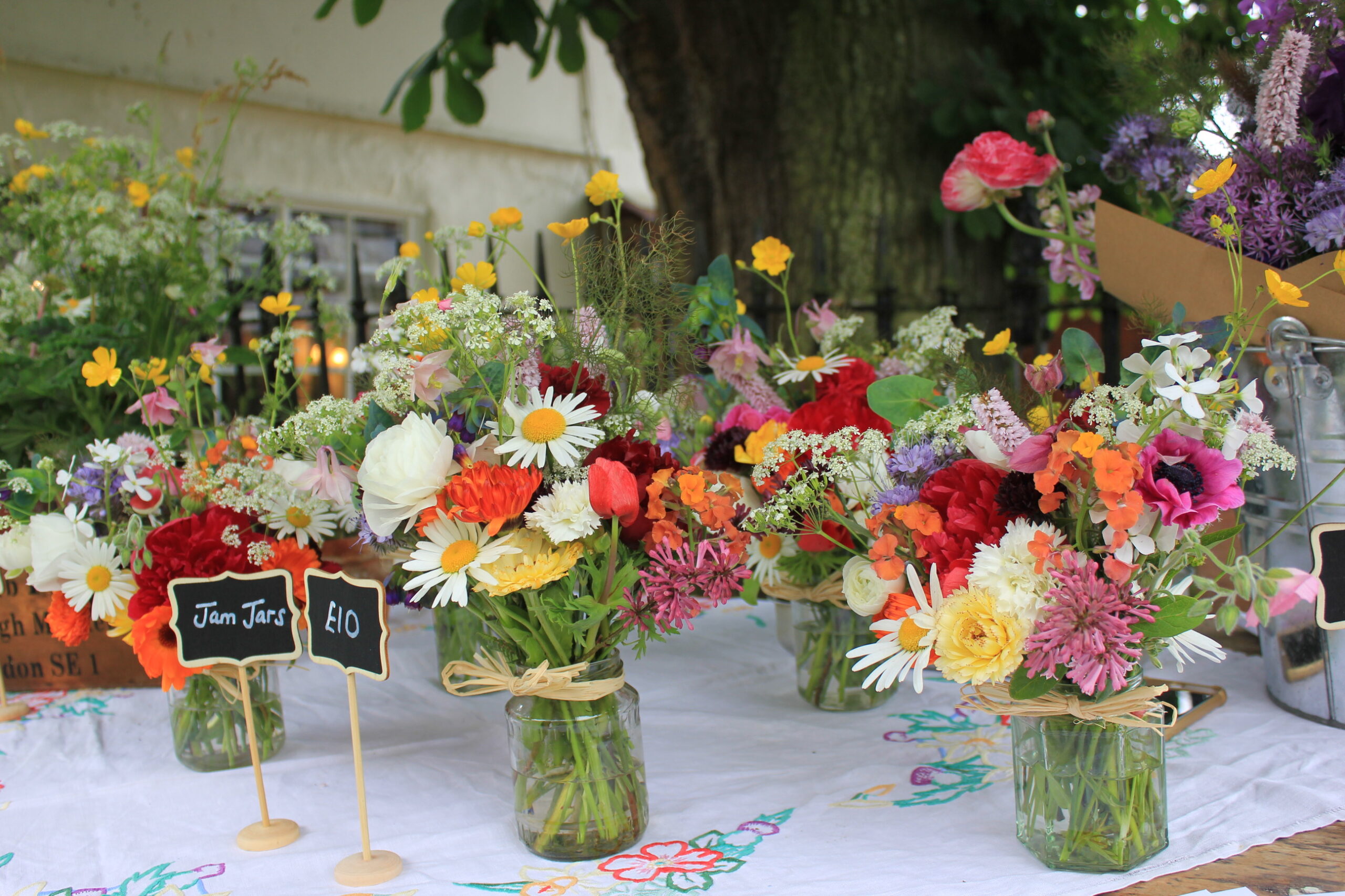 Jam jars of seasonal British flowers being sold at market