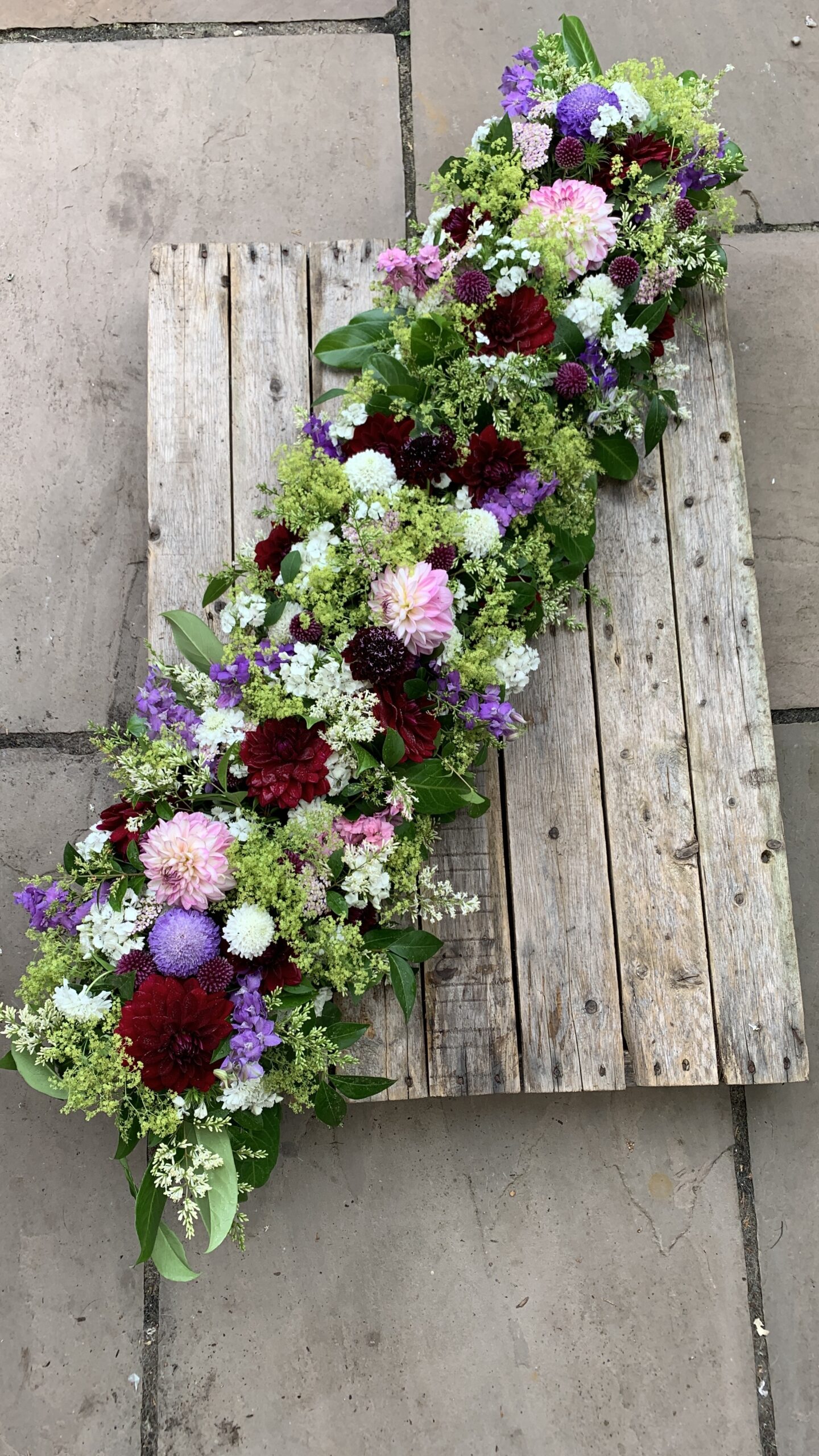 A seasonal casket arrangement of British flowers designed by The Posy Patch