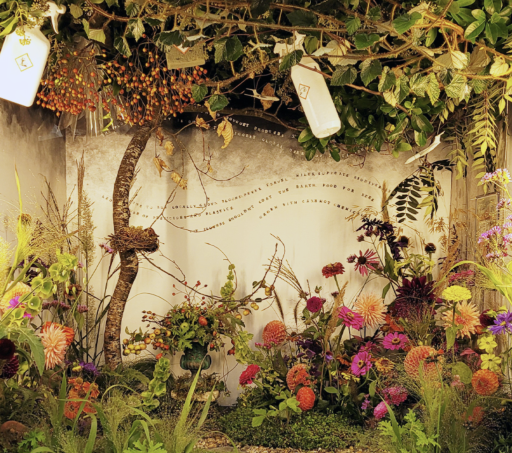 An imaginative autumn display by the Fairford Flower Collective featuring dahlias, crab apples, grasses and messages about the sustainability of the floristry industry