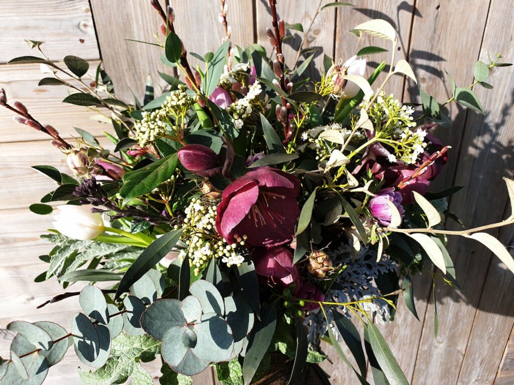 Red hellebores, salix and foliage in an early spring bouquet.