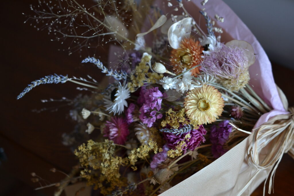 A dried flower bouquet of purple, white and yellow flowers.