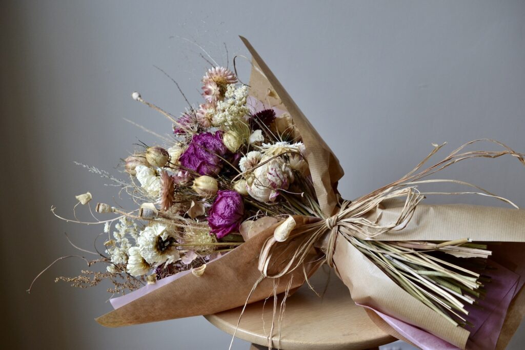 A dried flower bouquet of pink and white flowers, wrapped in paper, by Harebell and Bee.