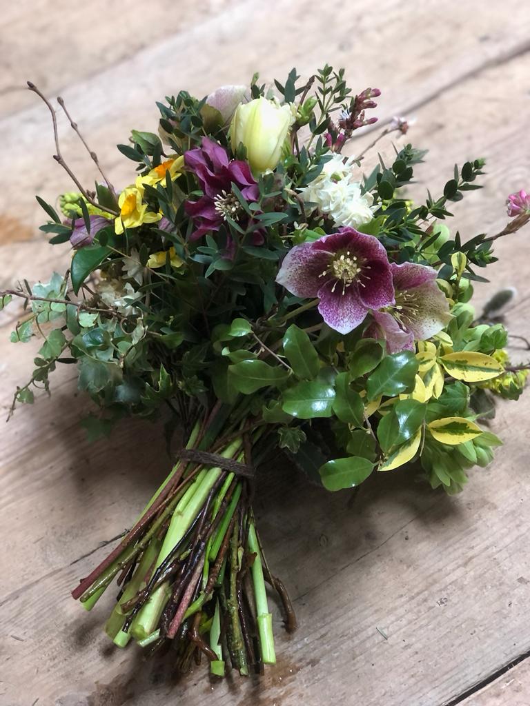 A winter bridal bouquet of pink, white and yellow flowers and green foliage by Wye Valley Flowers.