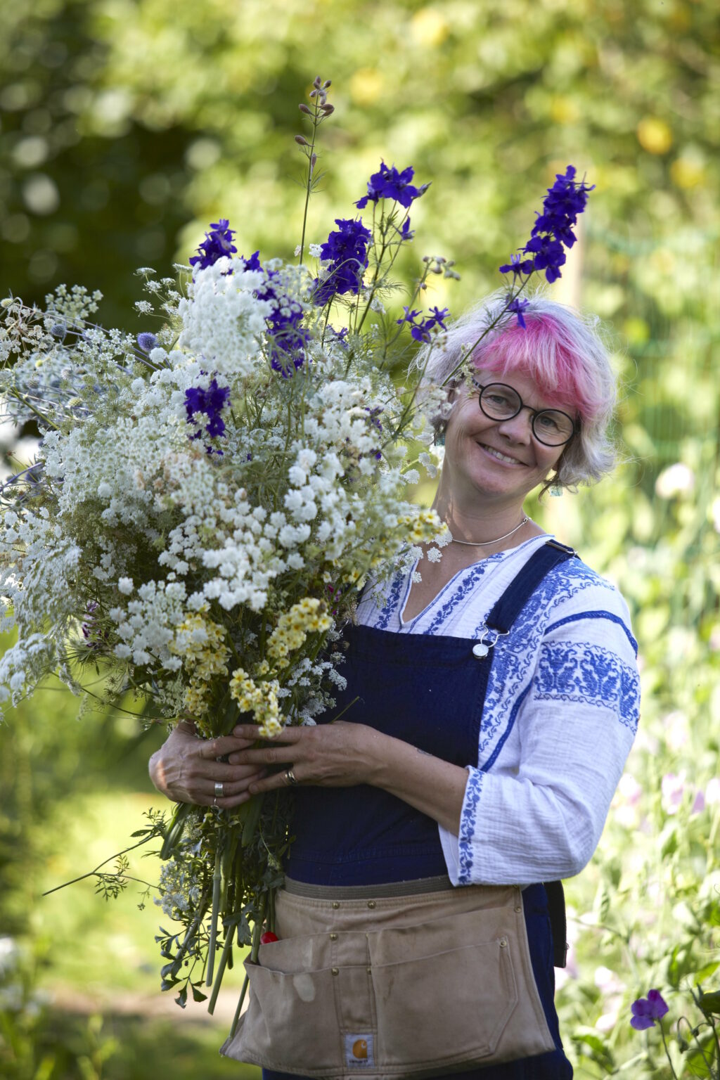 Fion Hazer-Bizony holds armfuls of blue larkspur and white ammi