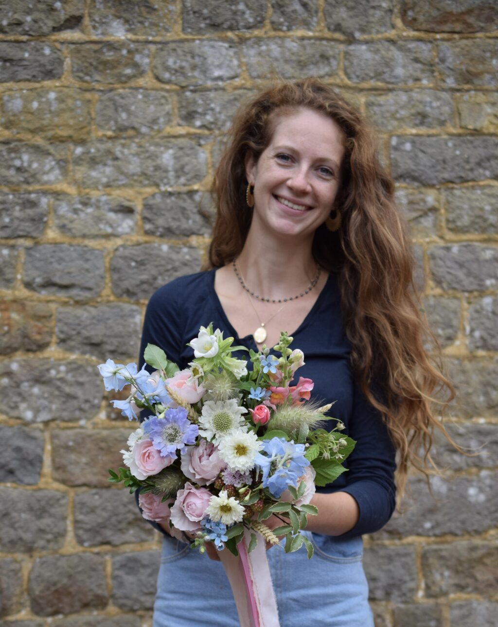 Alice Ancliff of Meadowfolk holds an early summer bouquet of mixed pale pink and blue flowers