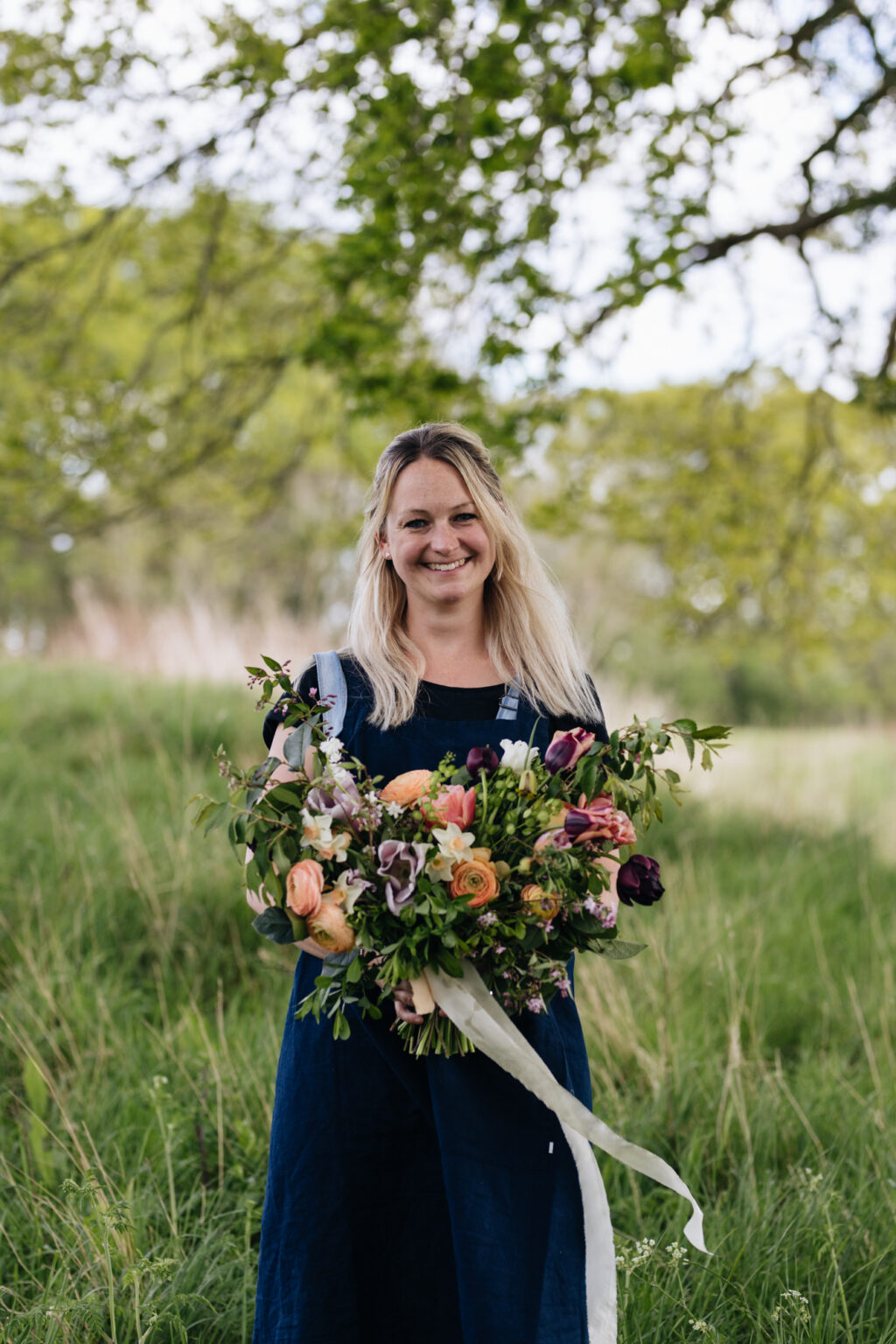 Katie Stone of Featherstone Flower Company pictured with a late spring bouquet of dark tulips and pale ranunculus