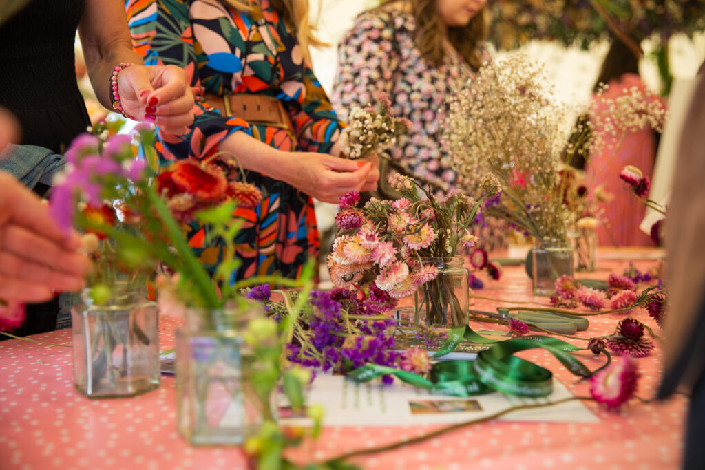 Members of the public making buttonholes and corsages from seasonal British flowers at the RHS Flower School at Hampton Court