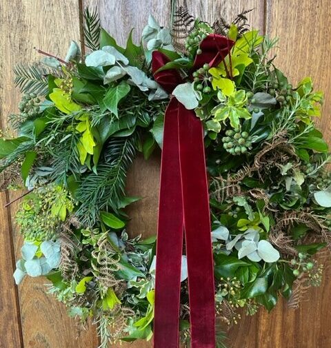 A beautiful fresh foliage Christmas wreath with sumptuous red velvet ribbon, made by Sarah Lockyer of Sarah's Flower Patch