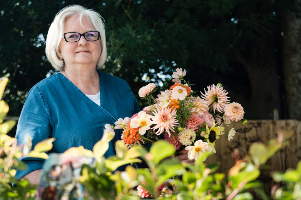 Sarah of Compton Garden Flowers holds a summer bouquet of peachy dahlias