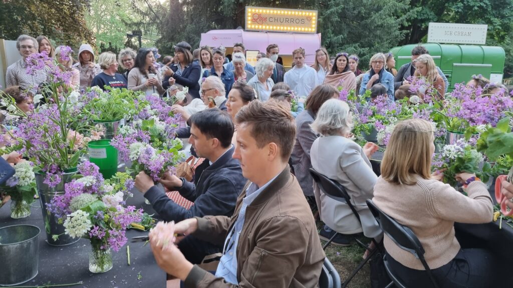 RHS Chelsea visitors sit at tables to make posies of albums, orlaya and seasonal British blooms with Featherstones English Flower Company.