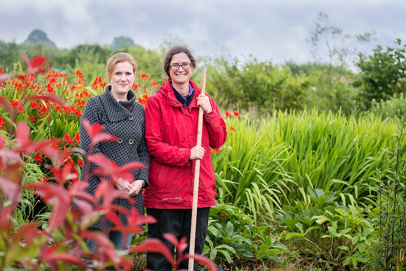 Cousins Jen and Ben of Blooming Green stand in their flower field surrounded by colourful foliage